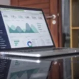 Laptop on desk showing graphs