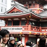 crowd walking in front of a red building of traditional Japanese architecture
