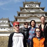 group of students smiling in front of a castle in Japan