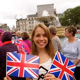 student in a parade crowd holding two Union Jack flags