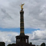 Monument in Berlin with a circular columned base and a tall tower topped with a golden angel