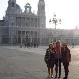three students standing in a plaza in Madrid with the Almudena Cathedral behind them