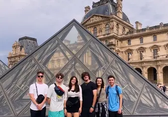 A group stands for a photo in front of the Louvre Pyramid