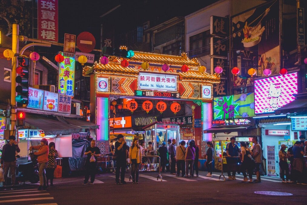 Photo by Vernon Raineil Cenzon on Unsplash Neon signs glow around the entrance to a night market in Taiwan.