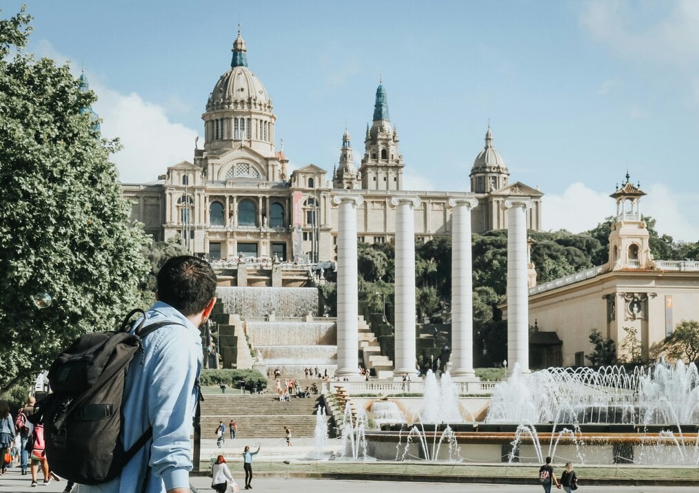 A man with a backpack looks at the exterior of the art museum in Barcelona.