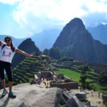 woman standing with arms out by her sides in front of macchu pichu