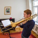 student playing the trombone in a cozy practice room 