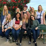 group of students sitting on and standing behind a bench in a park in Paris