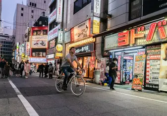 A man on a bike rides through the streets in Japan.