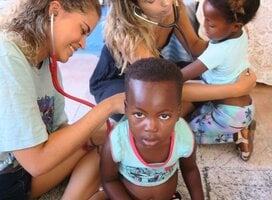 Two Volunteers doing a health screen of the children at the kindergarten