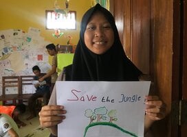 Student holding a 'Save the Jungle' Poster