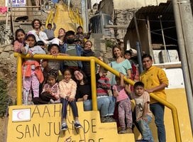 Children and volunteers in group on the stairs near the classroom