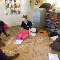 Zoe is sitting with 3 Community Health Workers on a mat, they are doing an activity that matches up cards