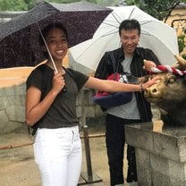 Grace touching a bull statue at Dazaifu shrine with her host dad in the background